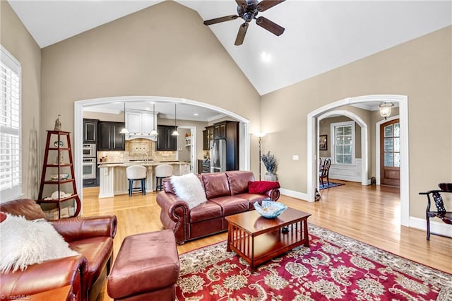 living room featuring high vaulted ceiling, light hardwood / wood-style floors, and ceiling fan