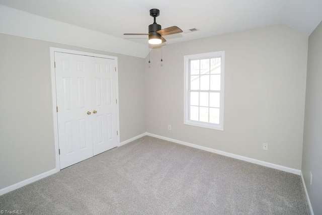 unfurnished bedroom with vaulted ceiling, light colored carpet, ceiling fan, and a closet