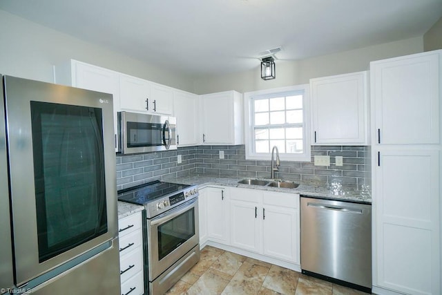 kitchen featuring white cabinetry, sink, backsplash, light stone counters, and stainless steel appliances