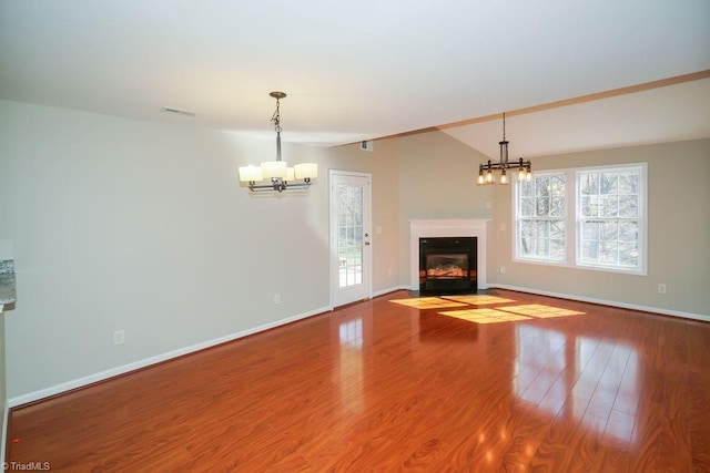 unfurnished living room featuring lofted ceiling, a chandelier, and hardwood / wood-style floors