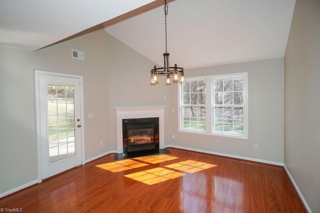 unfurnished living room with hardwood / wood-style flooring, plenty of natural light, vaulted ceiling, and a notable chandelier