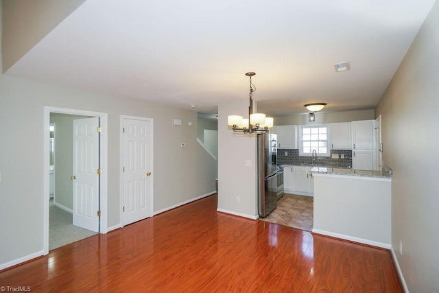 kitchen featuring tasteful backsplash, decorative light fixtures, stainless steel fridge with ice dispenser, light hardwood / wood-style flooring, and white cabinets