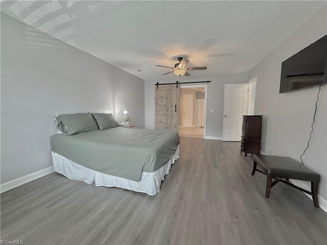 12 Cedar Knoll Ct Unit 12, Greensboro, NC 27407 - bedroom featuring wood finished floors, a textured ceiling, a barn door, and ceiling fan