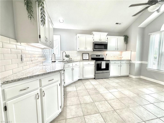 12 Cedar Knoll Ct Unit 12, Greensboro, NC 27407 - kitchen with appliances with stainless steel finishes, vaulted ceiling, white cabinetry, light stone counters, and a ceiling fan