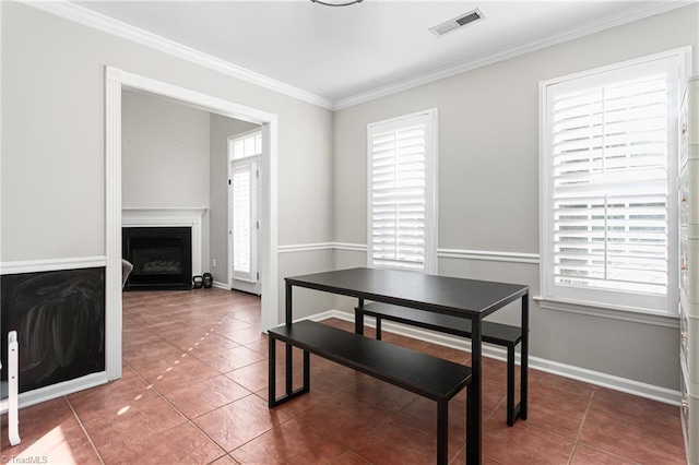 tiled dining area with crown molding, baseboards, visible vents, and a fireplace