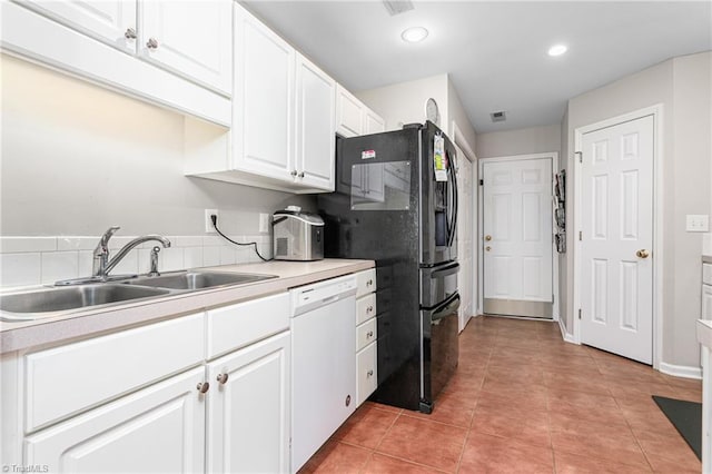 kitchen featuring freestanding refrigerator, white dishwasher, light countertops, white cabinetry, and a sink