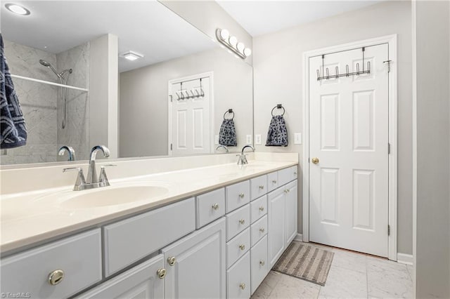 bathroom with double vanity, a sink, marble finish floor, and walk in shower