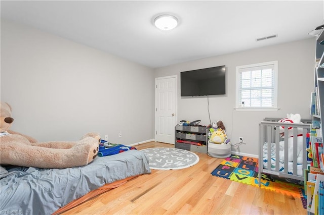 bedroom featuring baseboards, wood finished floors, and visible vents