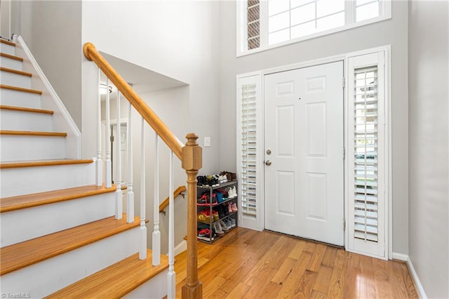 entrance foyer with a towering ceiling, stairway, and light wood-style floors