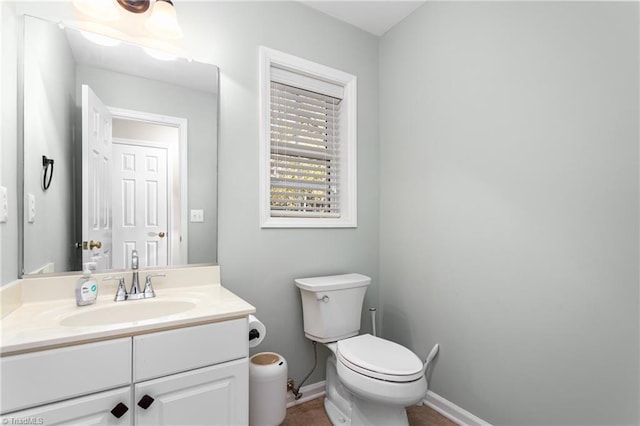 half bath featuring vanity, baseboards, and toilet