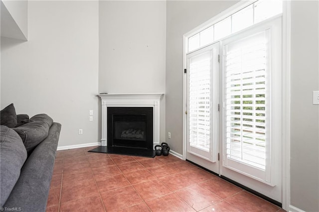 living area featuring a fireplace with raised hearth, tile patterned floors, and baseboards