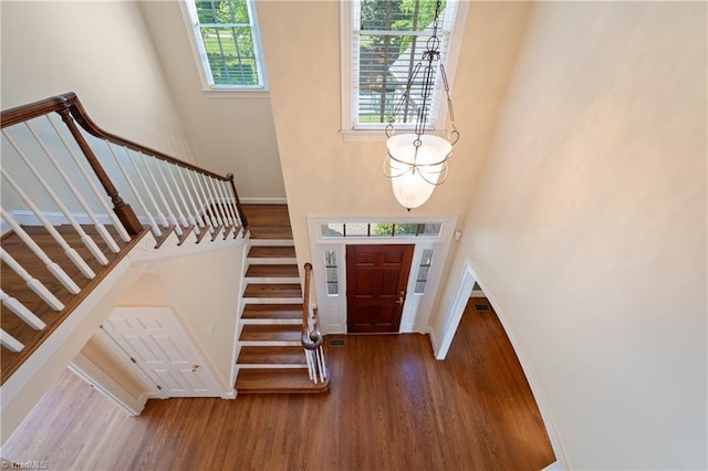entryway featuring stairway, baseboards, wood finished floors, and a towering ceiling