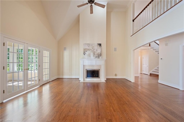 unfurnished living room featuring wood finished floors, a fireplace with flush hearth, and a high ceiling