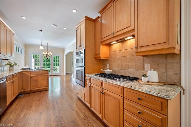 kitchen with light stone countertops, a chandelier, tasteful backsplash, light wood-style flooring, and stainless steel appliances