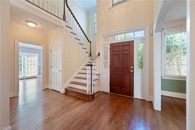 foyer featuring stairs, baseboards, ornamental molding, and wood finished floors