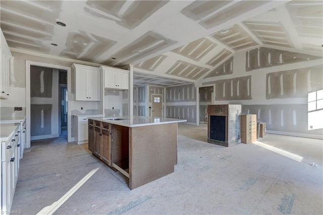 kitchen with white cabinetry, a center island, and vaulted ceiling