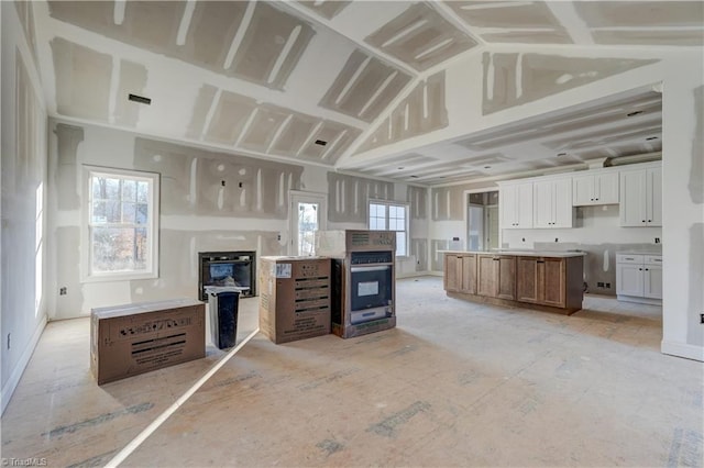 kitchen featuring a healthy amount of sunlight, lofted ceiling, white cabinetry, and a spacious island