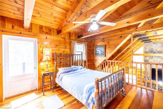 bedroom with lofted ceiling with beams, wood ceiling, wood walls, and hardwood / wood-style flooring