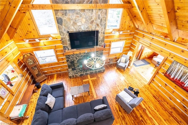 unfurnished living room with a fireplace, lofted ceiling with beams, wooden walls, wooden ceiling, and hardwood / wood-style floors