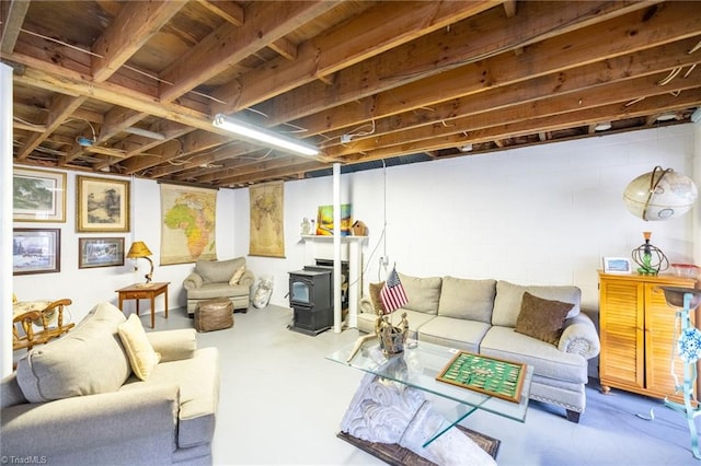 living area with a wood stove, concrete flooring, and concrete block wall