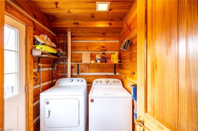 clothes washing area featuring wooden walls, wood ceiling, laundry area, and washer and clothes dryer