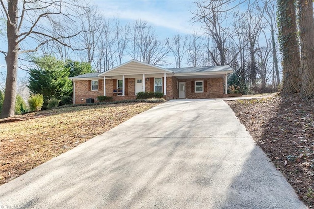 ranch-style house featuring covered porch, concrete driveway, and brick siding