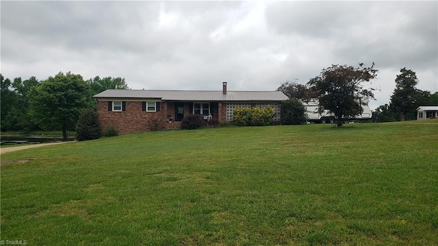 ranch-style home featuring brick siding, a chimney, and a front yard