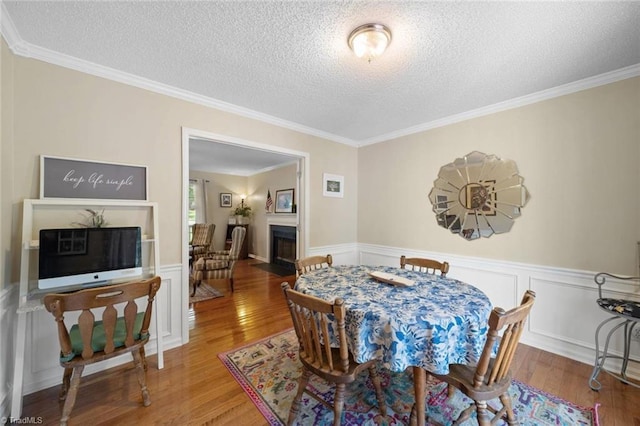4012 Clarendon Ave, Winston-Salem, NC 27106 - dining room with wood finished floors, a textured ceiling, ornamental molding, a fireplace with flush hearth, and wainscoting