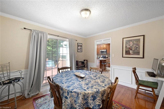4012 Clarendon Ave, Winston-Salem, NC 27106 - dining area with a textured ceiling, wood finished floors, wainscoting, crown molding, and a decorative wall