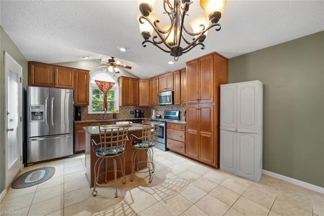 4012 Clarendon Ave, Winston-Salem, NC 27106 - kitchen with stainless steel appliances, vaulted ceiling, backsplash, brown cabinetry, and a center island