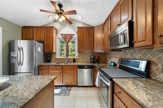 4012 Clarendon Ave, Winston-Salem, NC 27106 - kitchen featuring stainless steel appliances, vaulted ceiling, dark stone counters, brown cabinetry, and a ceiling fan