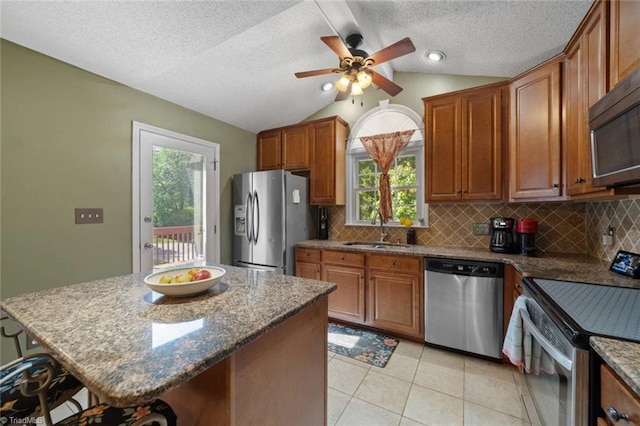 4012 Clarendon Ave, Winston-Salem, NC 27106 - kitchen with stainless steel appliances, decorative backsplash, brown cabinets, plenty of natural light, and vaulted ceiling