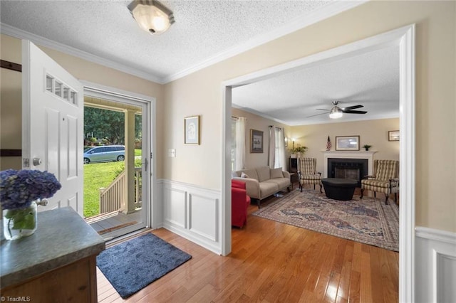 4012 Clarendon Ave, Winston-Salem, NC 27106 - entrance foyer featuring a textured ceiling, light wood finished floors, a ceiling fan, a wainscoted wall, and a fireplace