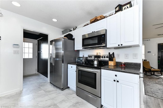 kitchen featuring dark countertops, recessed lighting, appliances with stainless steel finishes, marble finish floor, and white cabinetry