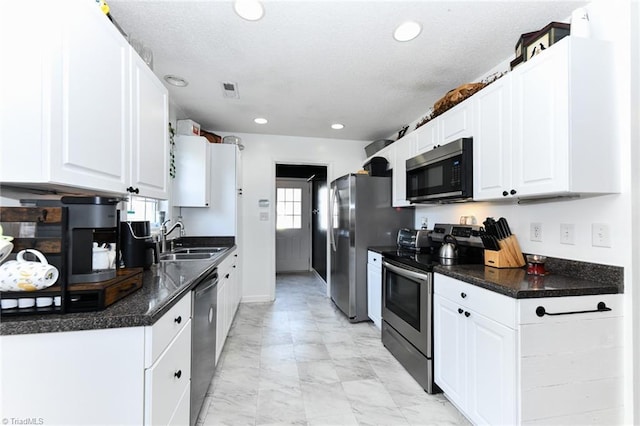 kitchen featuring a sink, stainless steel appliances, dark countertops, and white cabinetry