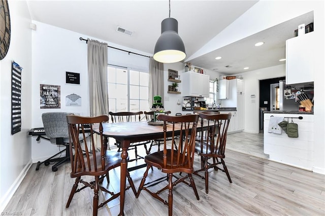 dining space with baseboards, visible vents, light wood finished floors, lofted ceiling, and recessed lighting