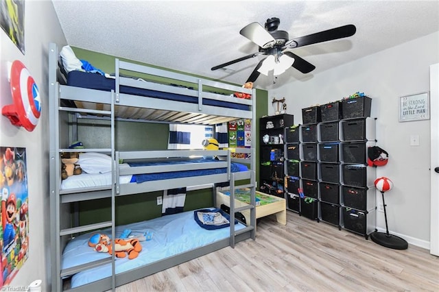 bedroom with a textured ceiling, baseboards, and wood finished floors