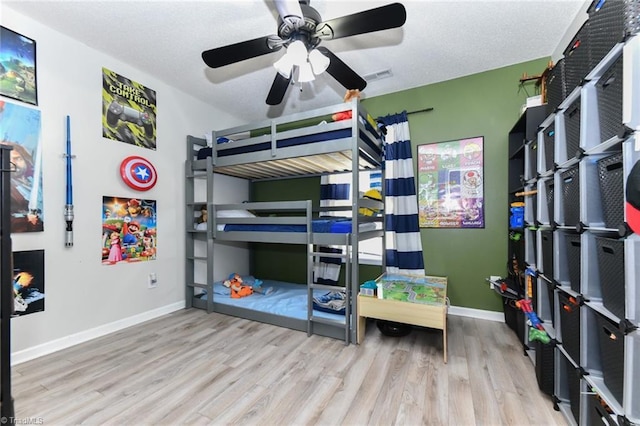 bedroom featuring a textured ceiling, wood finished floors, visible vents, and baseboards