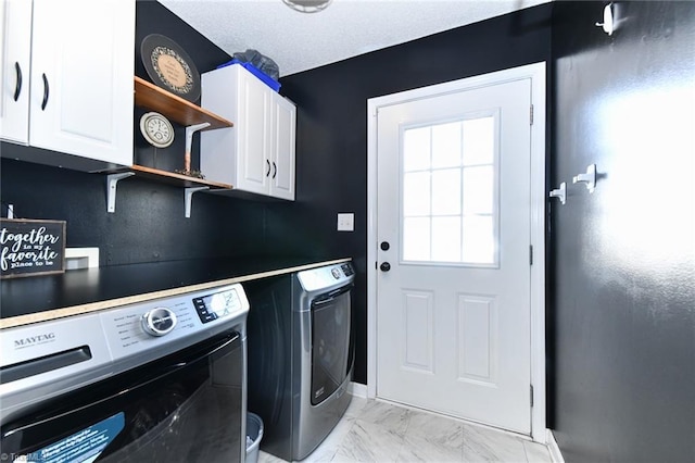 clothes washing area featuring independent washer and dryer, cabinet space, a textured ceiling, and marble finish floor