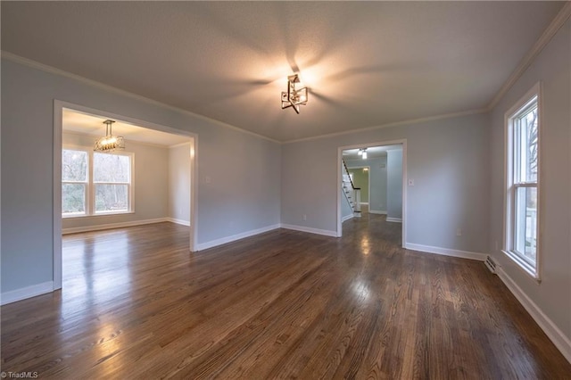 empty room with an inviting chandelier, dark wood-type flooring, and ornamental molding