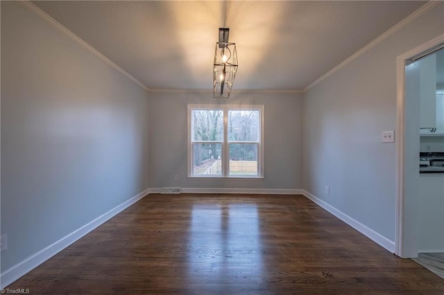 empty room featuring a chandelier, dark hardwood / wood-style floors, and ornamental molding