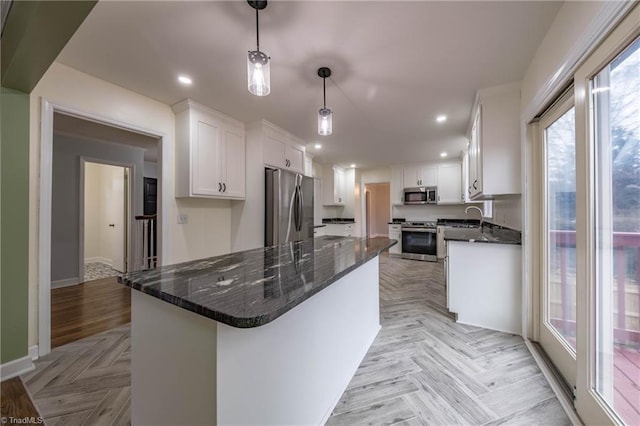 kitchen with sink, white cabinets, decorative light fixtures, light parquet flooring, and appliances with stainless steel finishes