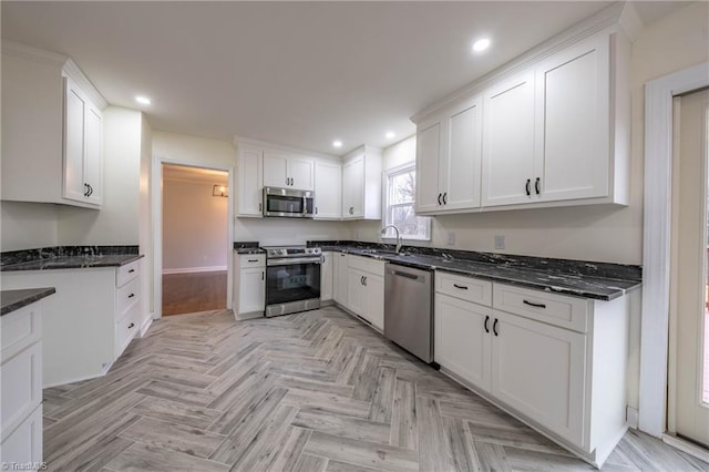 kitchen featuring white cabinets, sink, appliances with stainless steel finishes, and dark stone counters