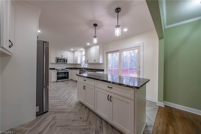 kitchen with pendant lighting, dark stone countertops, ornamental molding, white cabinetry, and stainless steel appliances