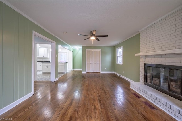 unfurnished living room with hardwood / wood-style floors, ceiling fan, ornamental molding, and a brick fireplace