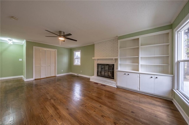 unfurnished living room featuring ceiling fan, a fireplace, dark wood-type flooring, and ornamental molding