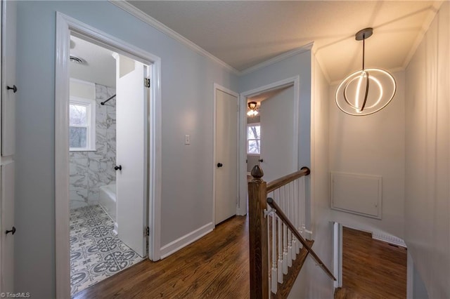 corridor with dark hardwood / wood-style floors, ornamental molding, and a notable chandelier