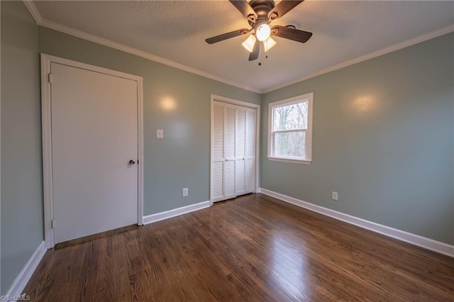 unfurnished bedroom with ceiling fan, crown molding, and dark wood-type flooring