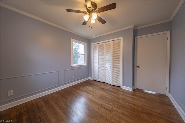 unfurnished bedroom with ceiling fan, dark hardwood / wood-style floors, crown molding, and a closet