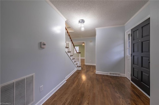 entrance foyer featuring a textured ceiling, crown molding, and dark hardwood / wood-style floors